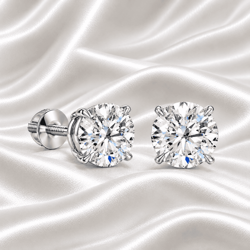 Pair of Gabriel Edward Jewelers classic round diamond stud earrings on white satin fabric